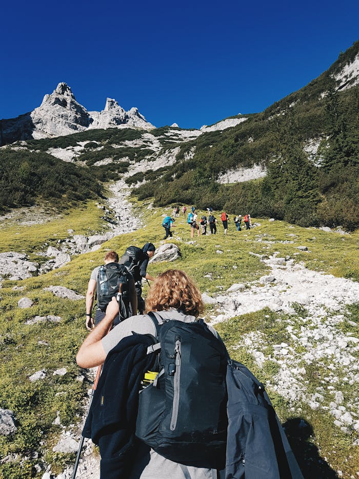 about-img-01 A group of hikers trekking through the rugged landscape of Garmisch-Partenkirchen, Germany under a clear blue sky.